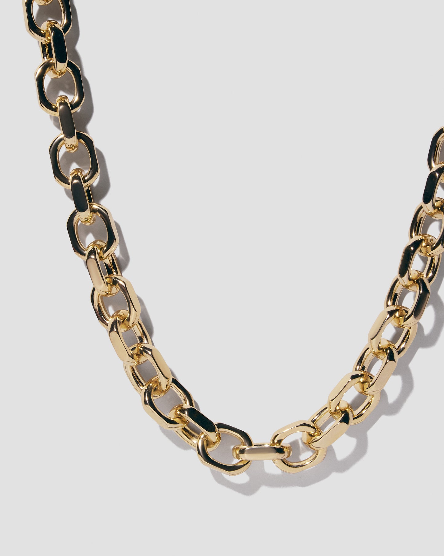 Necklace hanging on grey background.