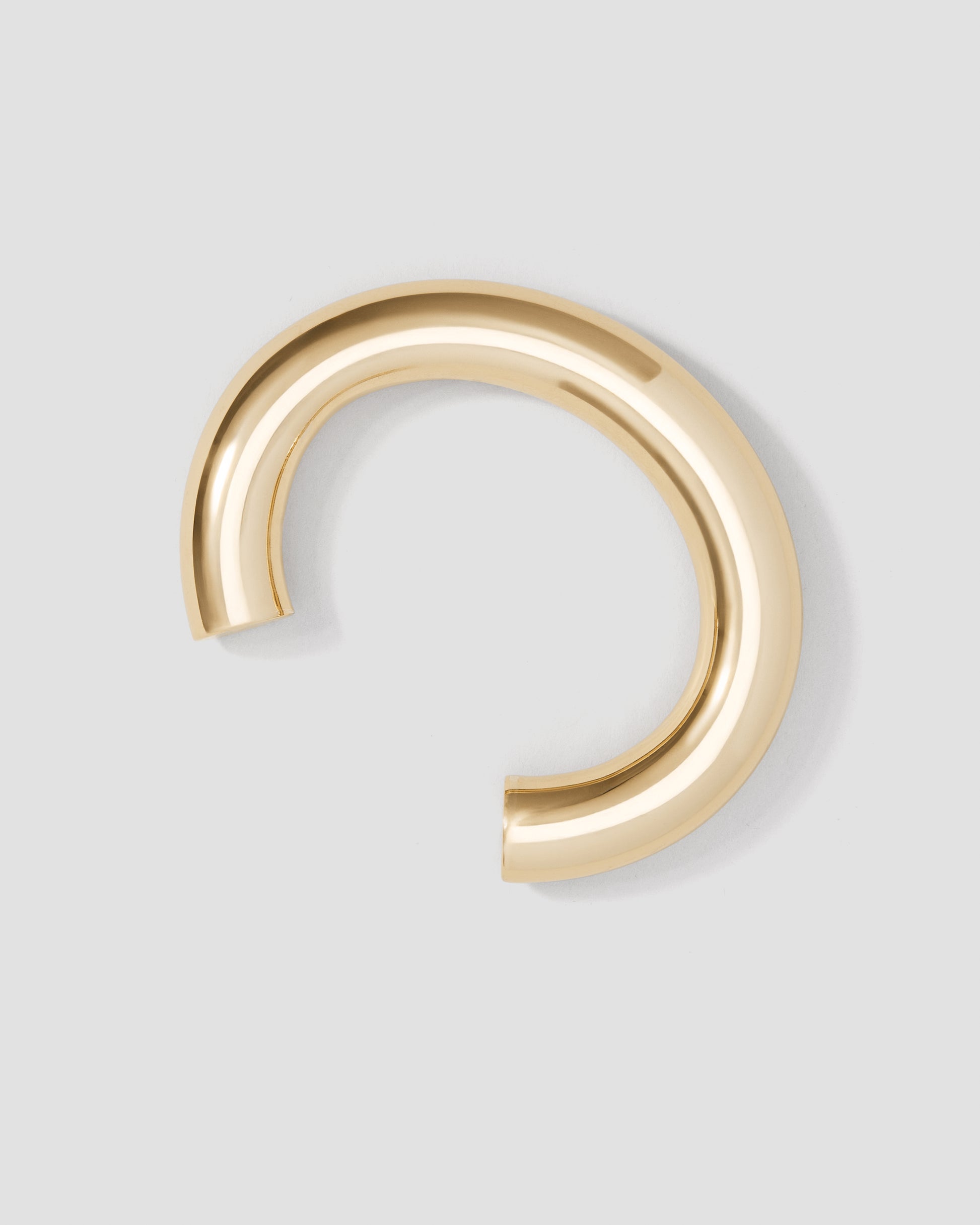 Gold hoop earring on a light gray background