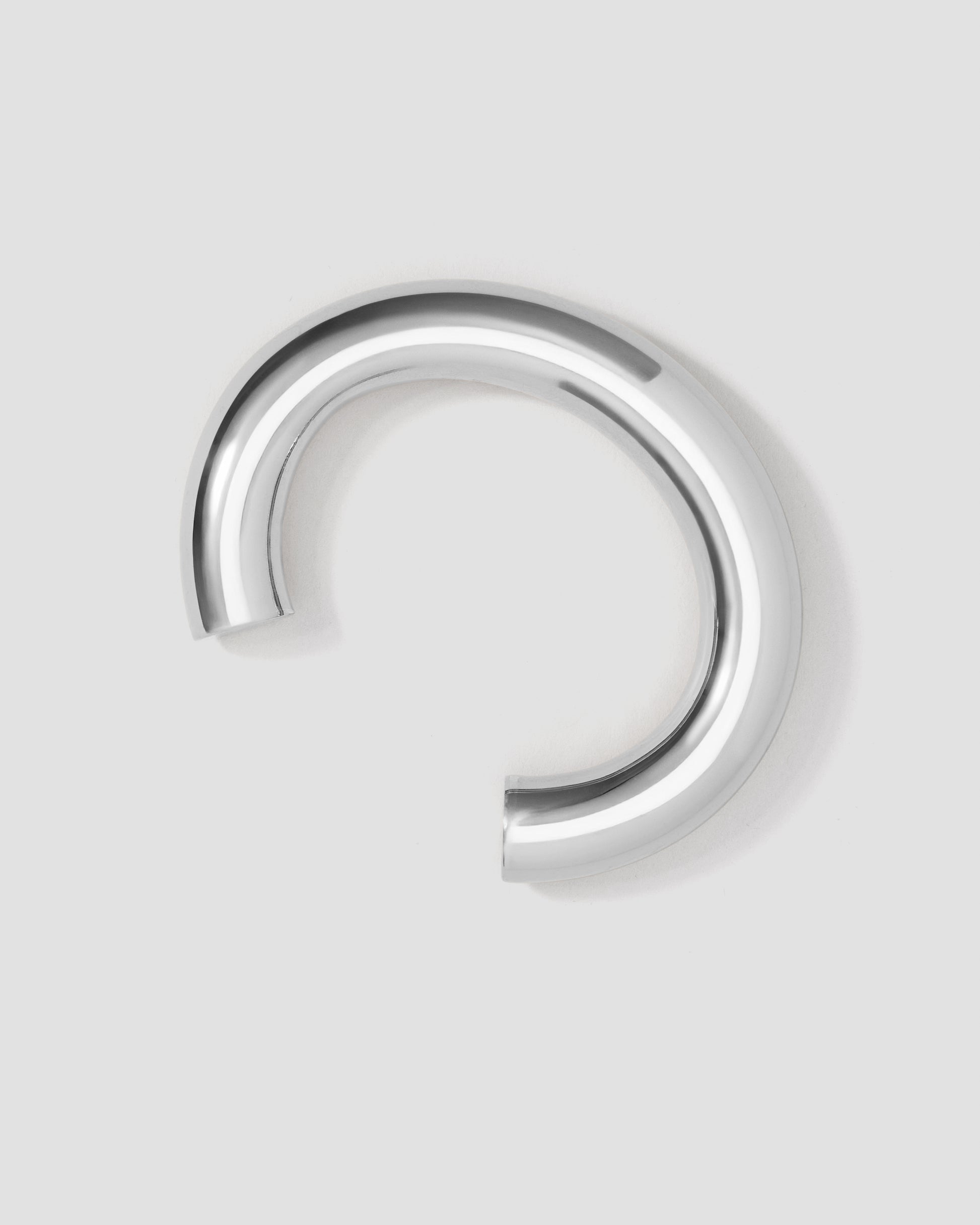 Silver circular earring on a light gray background
