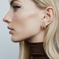 Image of model wearing brown top and wearing diamond huggie earrings