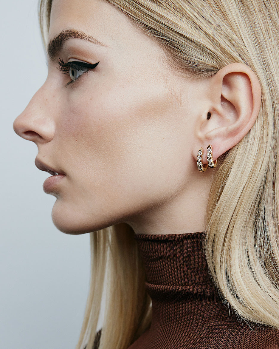 Image of model wearing brown top and wearing diamond huggie earrings