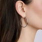 Silver hoop earring worn by a person with dark hair.
