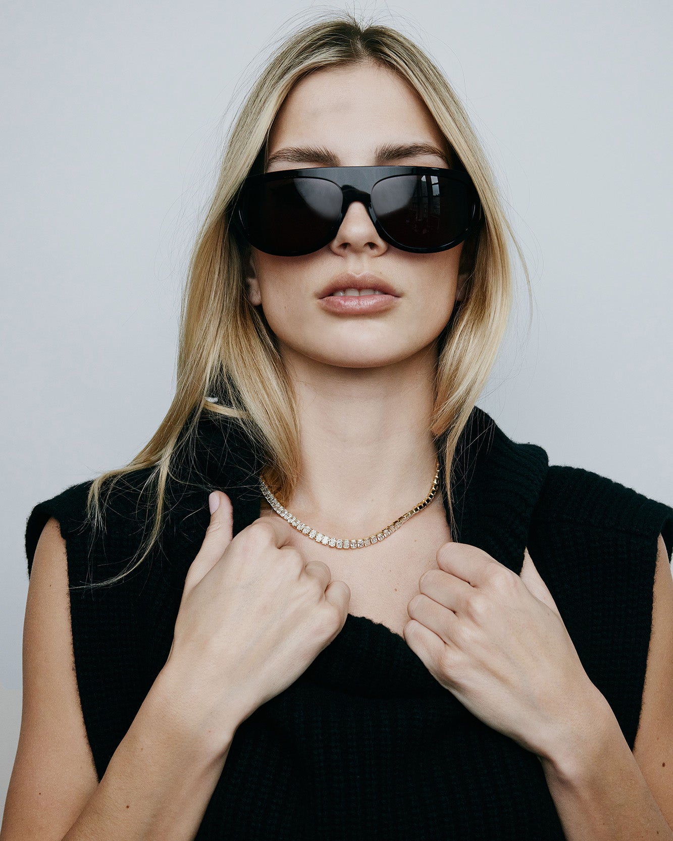 Model with black sunglasses and top wearing a diamond tennis necklace