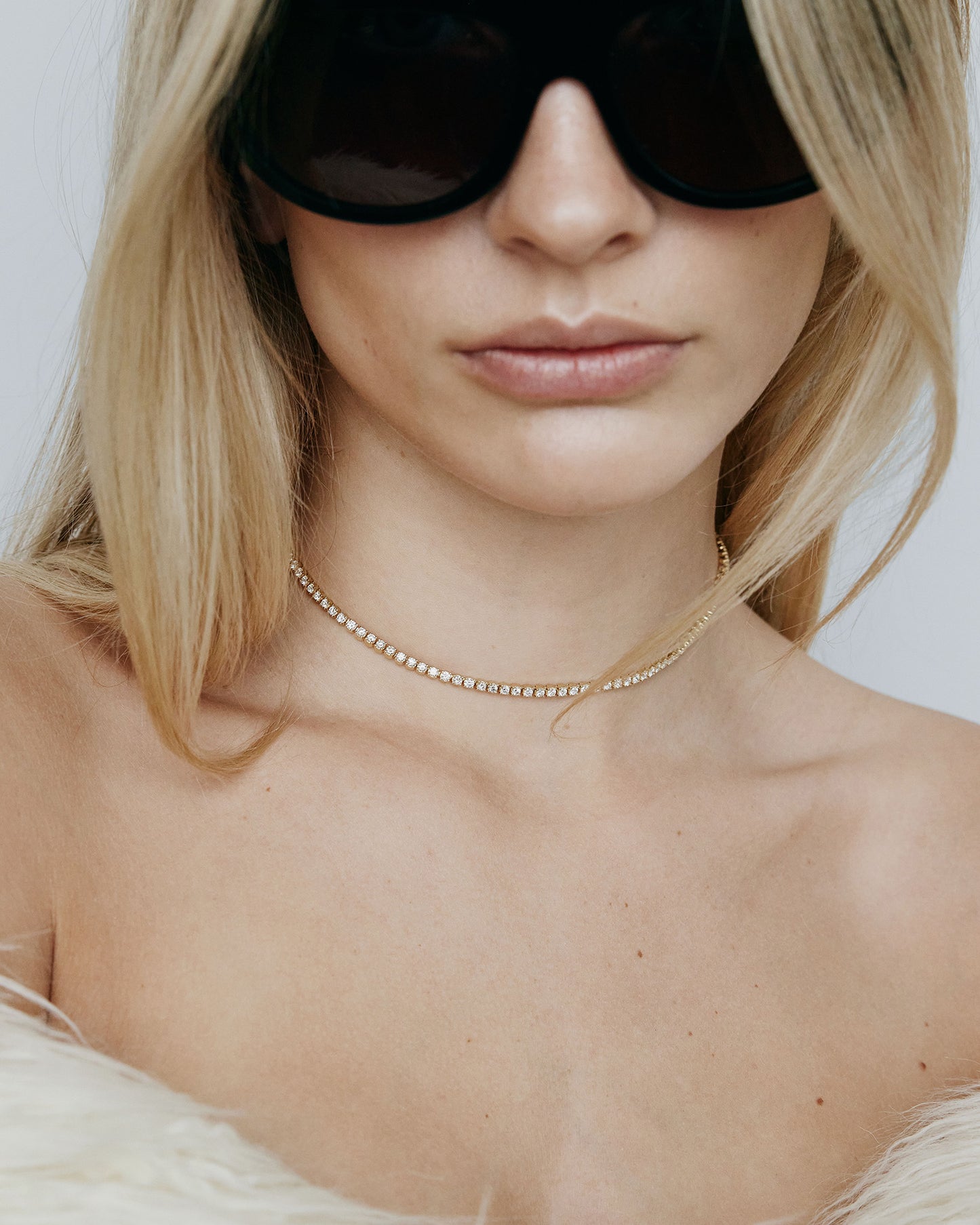 Image of model wearing sunglasses and diamond tennis necklace