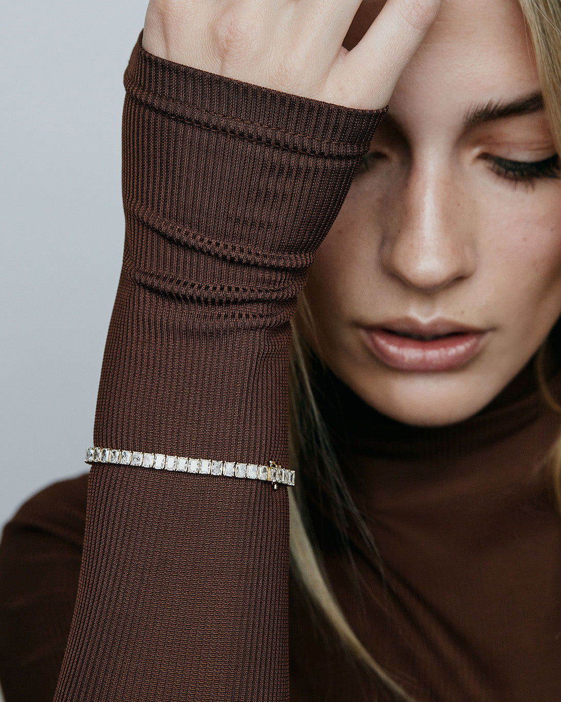 Model in brown top wearing rectangle shaped diamonds on a bracelet