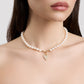 Pearl necklace with a heart-shaped charm worn by a model on a plain background