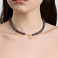 Pearl necklace with a gold evil eye pendant on a model against a neutral background