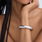 Close-up of a person wearing a silver bracelet on a neutral background