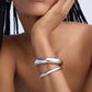 Silver bracelet on a wrist with a neutral background