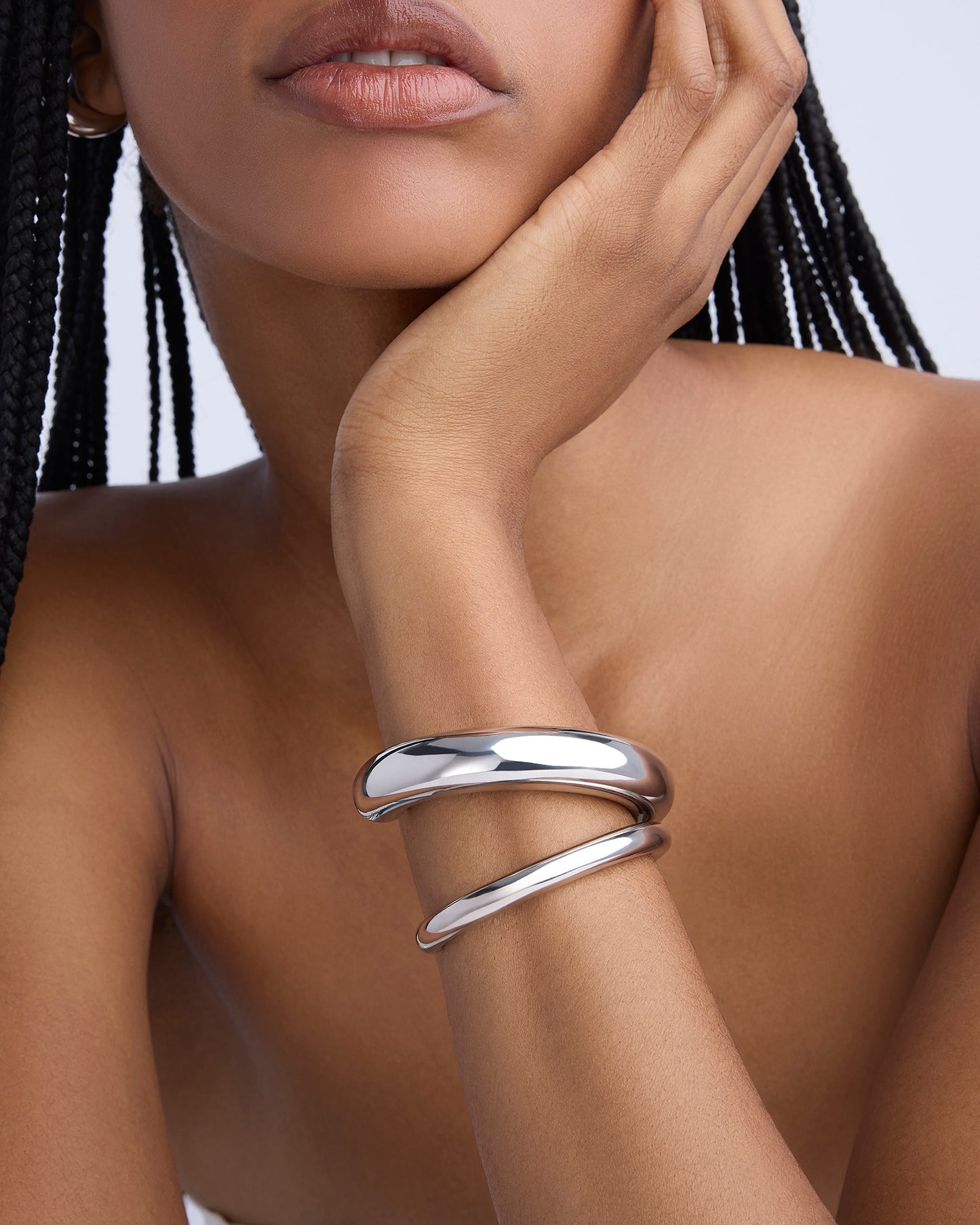 Silver bracelet on a wrist with a neutral background