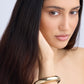 Woman wearing a gold bracelet on a plain background
