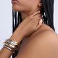 Woman wearing gold and silver bracelets on a plain background