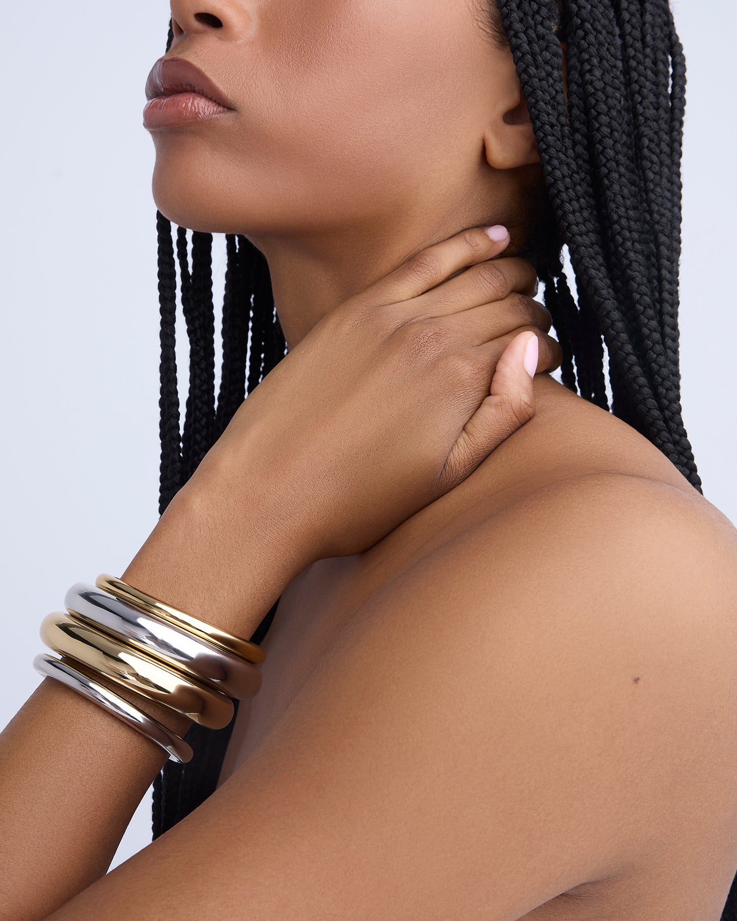 Woman wearing gold and silver bracelets on a plain background