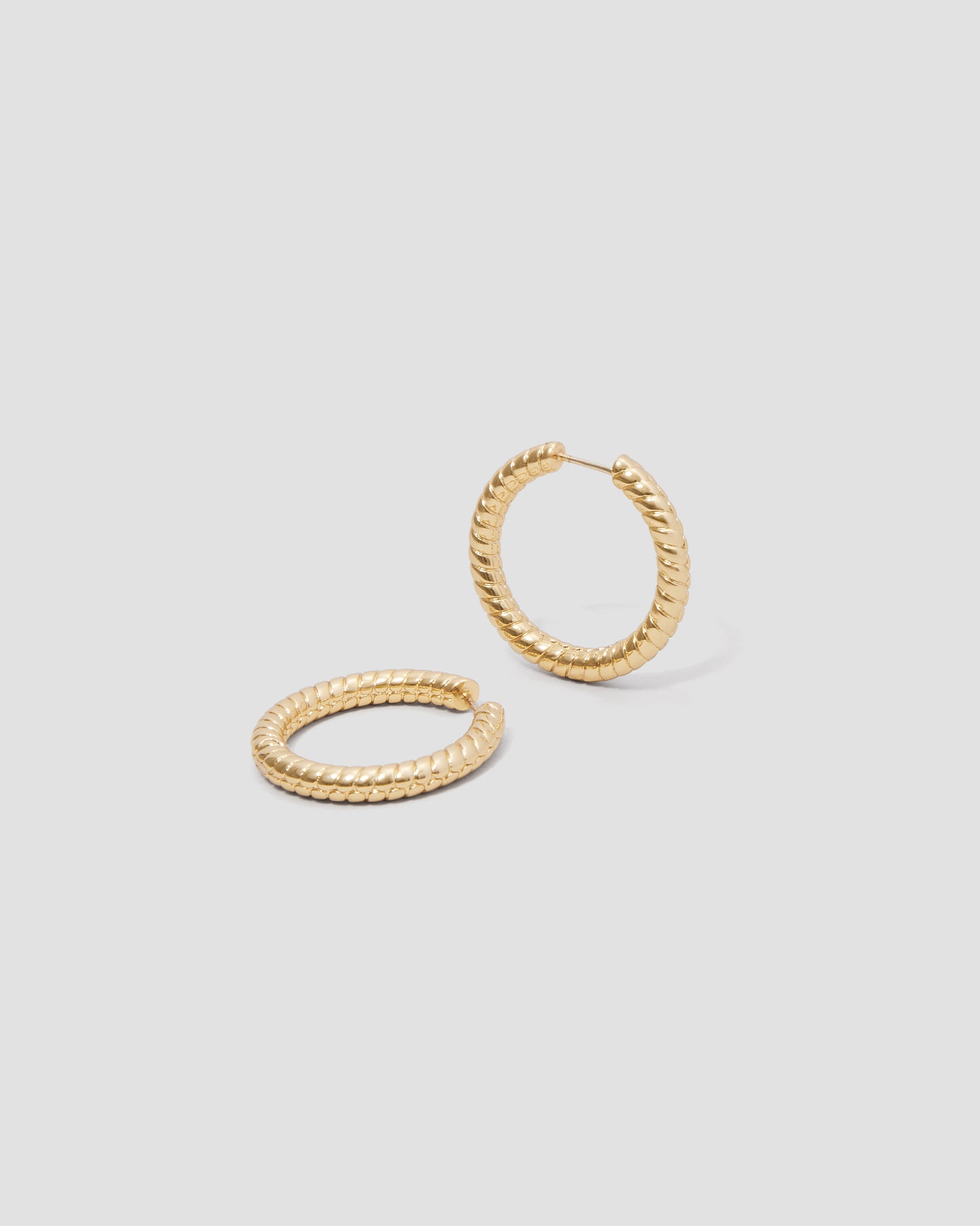 Gold hoop earrings on a light gray background